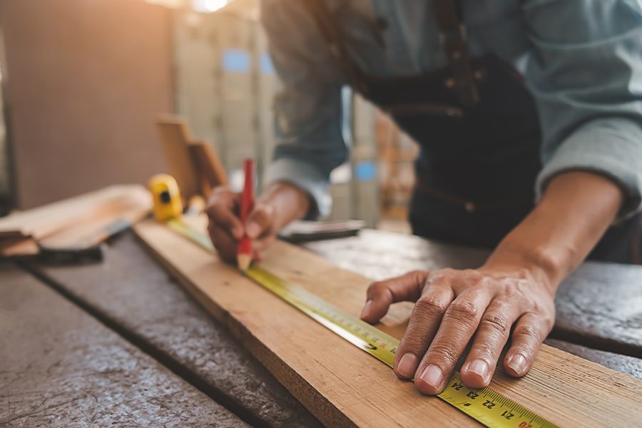 Carpenter Insurance - Carpenter Working With Equipment on Wooden Table in Workshop