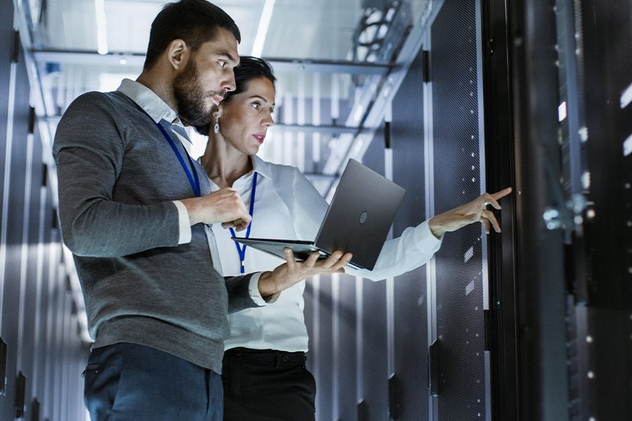 IT Contractor Insurance - IT Specialist Holding a Laptop in a Data Center with Colleague