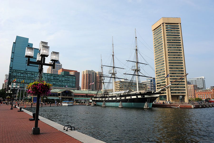 Client Center - Scenic View of Baltimore Maryland Harbor with a Historic Ship on the Dock Next to Commercial Buildings